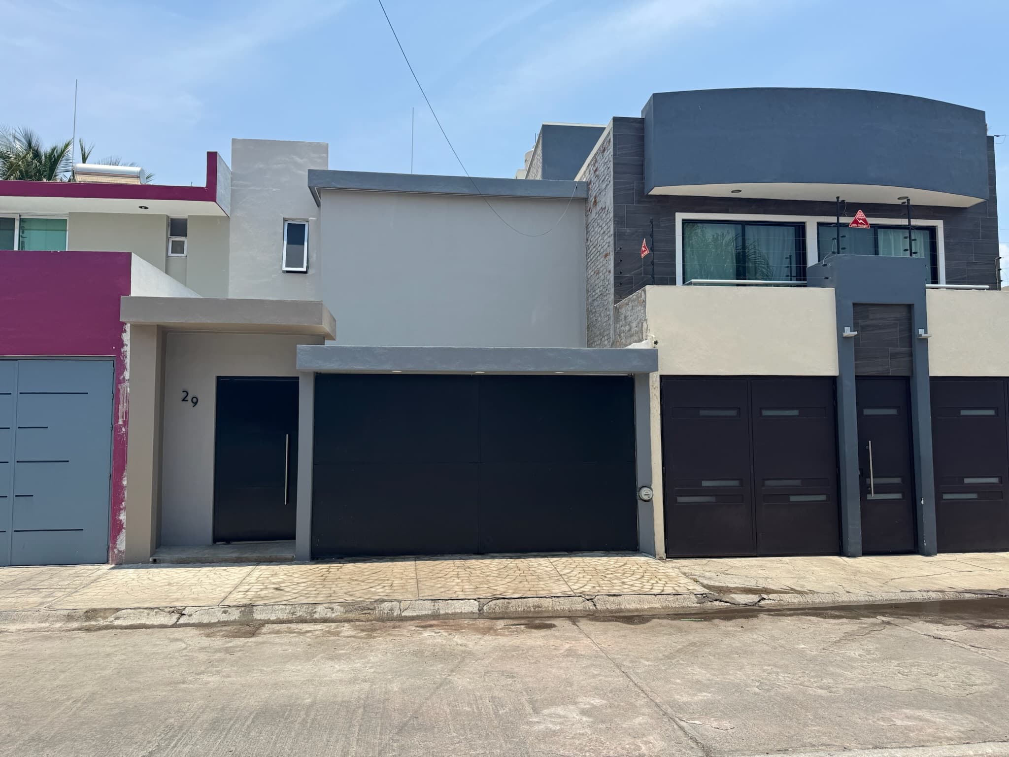 Fachada terminada de La Floresta con muros grises y portón negro